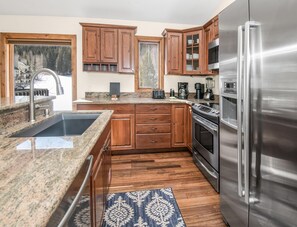A kitchen with granite countertops, wooden cabinets, a stainless steel refrigerator, and a built-in oven. - Timber Falls 1005, 3BD East Vail Condo With Amenities (Vail)
