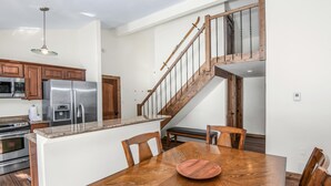 Eine moderne Küche mit Edelstahlgeräten, einem Holzespeisetisch und einer Treppe mit Holzhandläufen.