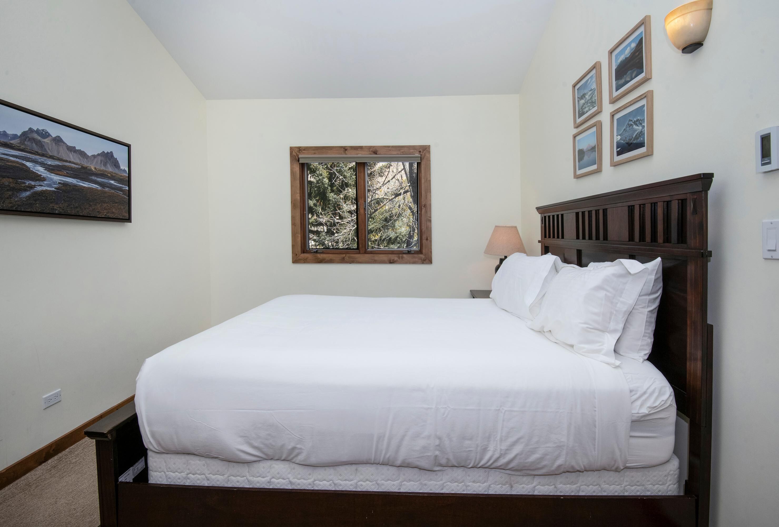 Un dormitorio con una cama grande, una ventana y cuadros en la pared.