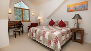 A bedroom with a bed, a desk, a chair, a lamp, and a painting on the wall.