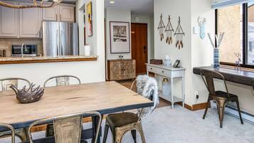 Una cocina moderna con electrodomésticos de acero inoxidable, una mesa de comedor de madera y un rincón de estar acogedor.