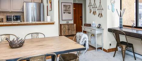 A modern kitchen with stainless steel appliances, a wooden dining table, and a cozy seating area.