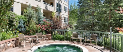 A multi-story building with a swimming pool, outdoor seating, and lush greenery.