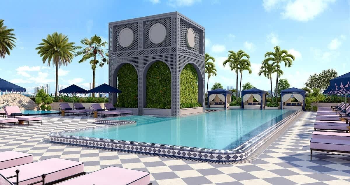 Uma área de piscina com espreguiçadeiras, borda decorativa e um edifício com arcos e vegetação.