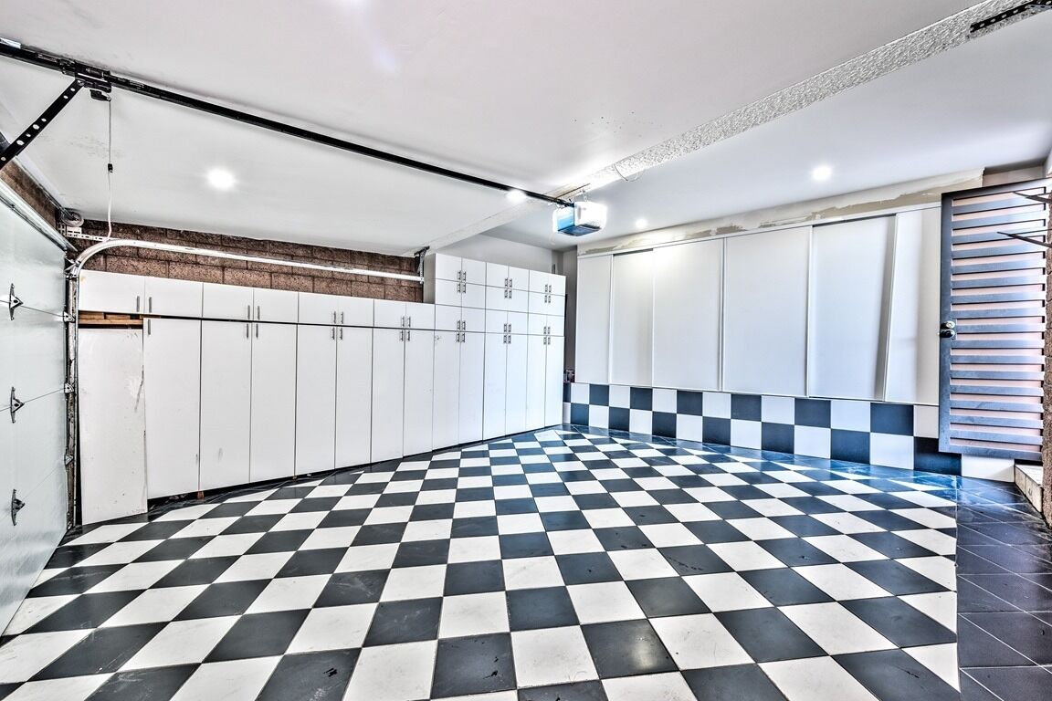 Ein geräumiges Zimmer mit Schachbrettmuster-Boden, weißen Schließfächern und einer Treppe.