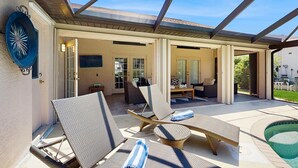 Un espace extérieur abrité comprenant des chaises longues, une piscine et une terrasse avec une table et des chaises pour les repas.
