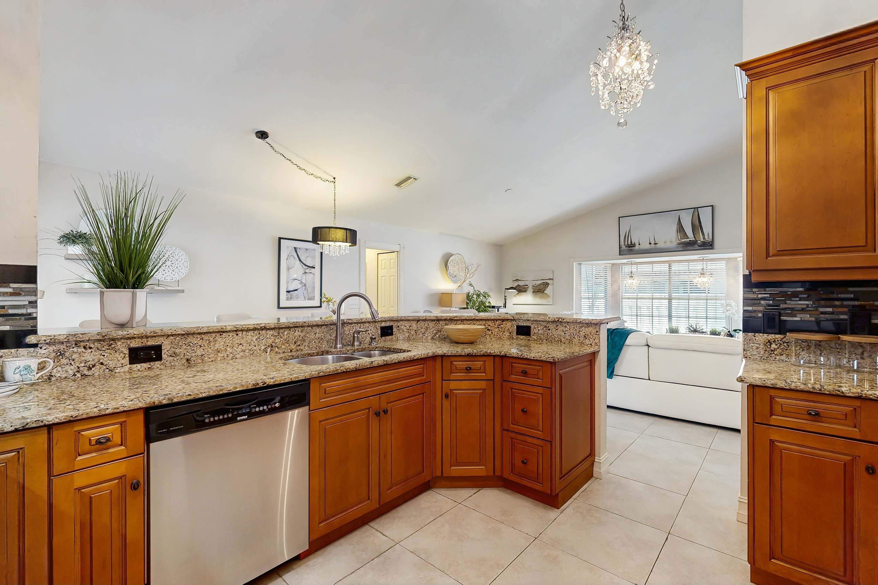 A kitchen with wooden cabinets, granite countertops, a dishwasher, and a chandelier.