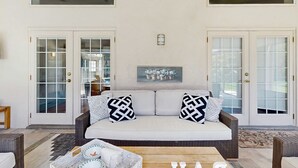 Un salon avec un canapé, deux coussins à motifs, une table basse et un tableau encadré accroché au mur.