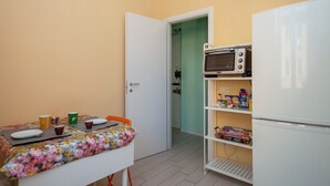 A small kitchenette with a microwave, a refrigerator, and a table with a floral tablecloth. - Renovated 2-bedroom apartment in the heart of Pigneto – sleeps 4 (Roma)