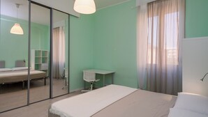 A bedroom with a bed, a desk, a chair, a wardrobe, and a mirror. - Renovated 2-bedroom apartment in the heart of Pigneto – sleeps 4 (Roma)