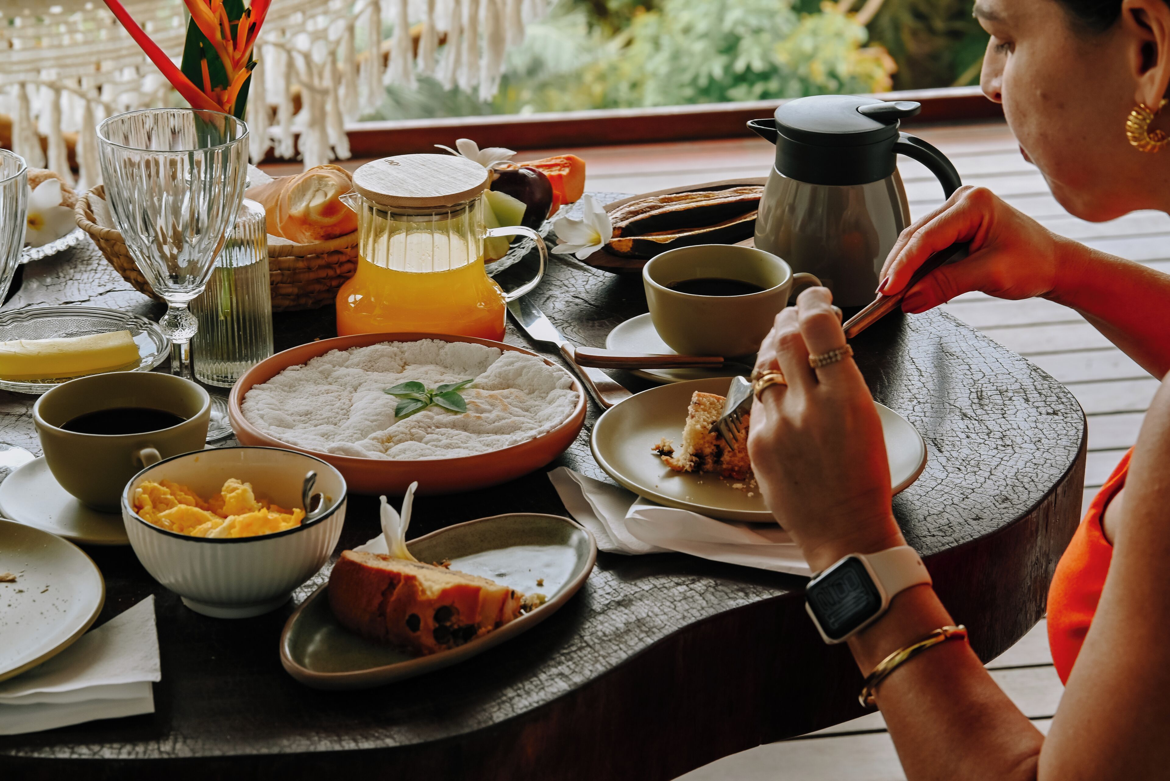 A dining table with various dishes, a coffee pot, and a person eating.