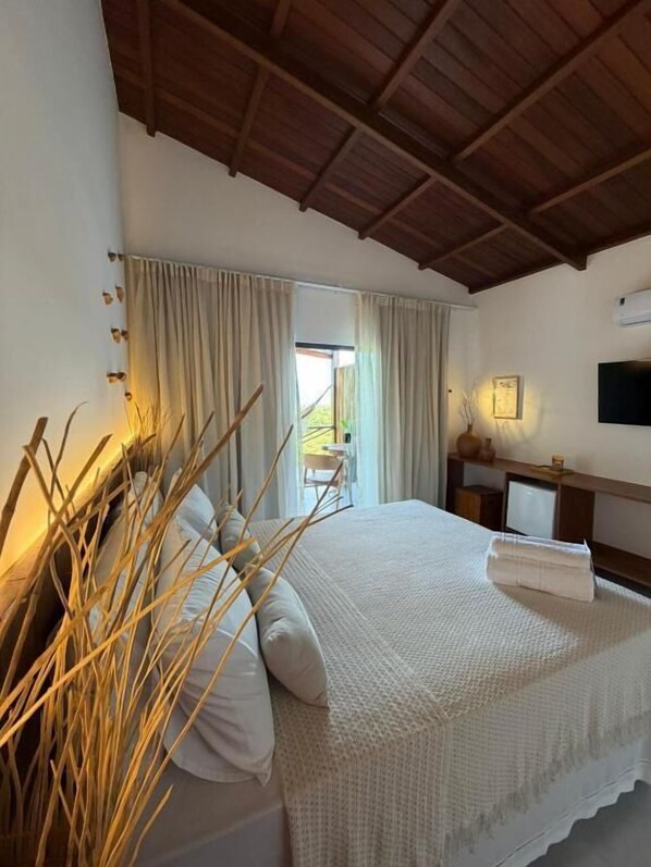 Un dormitorio con cama, cortinas, televisor y ventana.