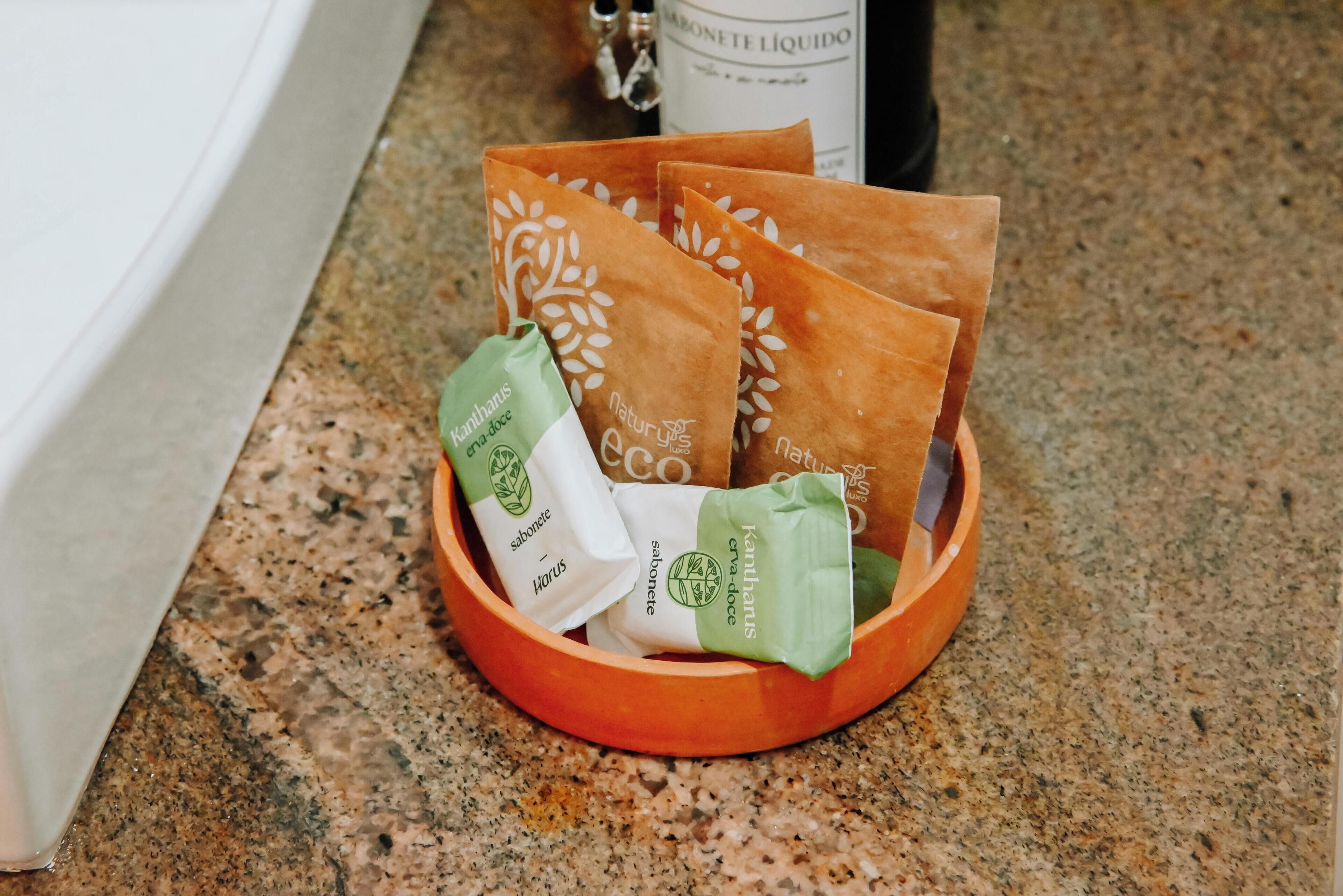 A wooden tray with several paper bags containing soap on a granite countertop.