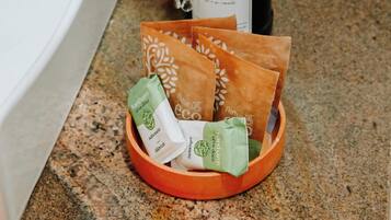 A wooden tray with several paper bags containing soap on a granite countertop.