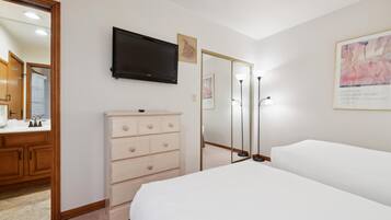 A bedroom with a bed, dresser, mirror, TV, and artwork.