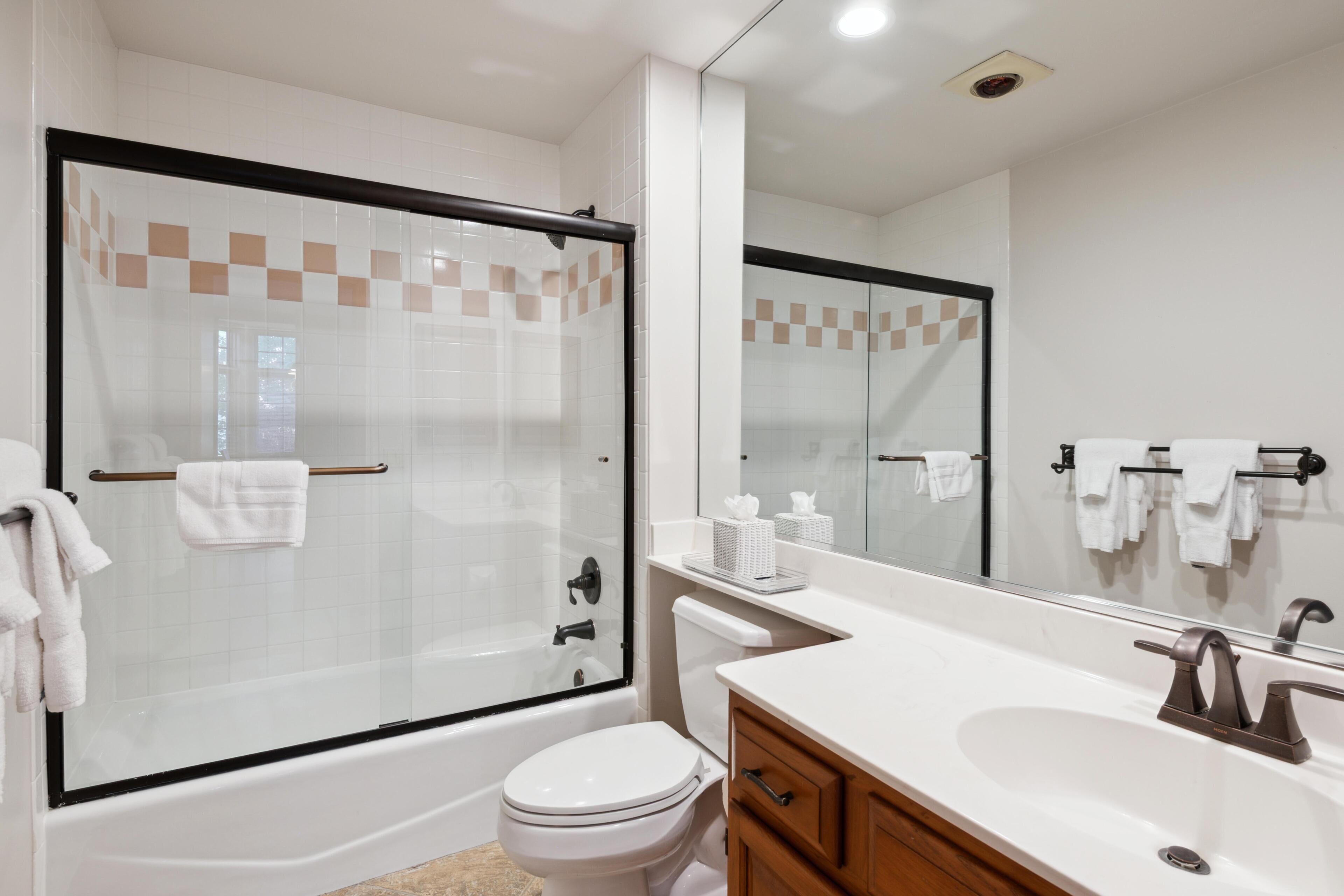Un bagno moderno con doccia vetrata, un water bianco, un mobile lavabo e un grande specchio.