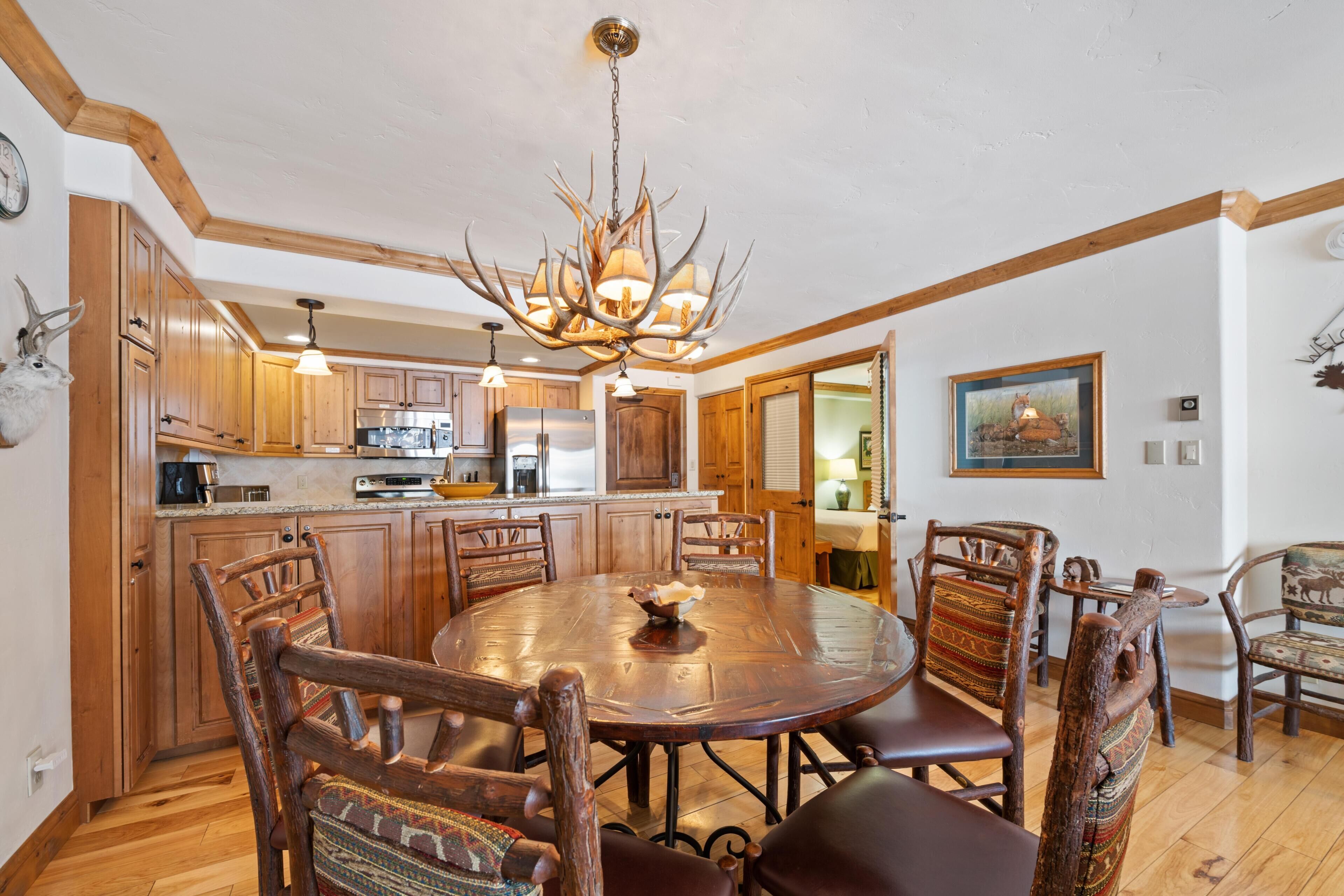 A dining area with a round wooden table, wooden chairs, a chandelier, and wooden cabinets.