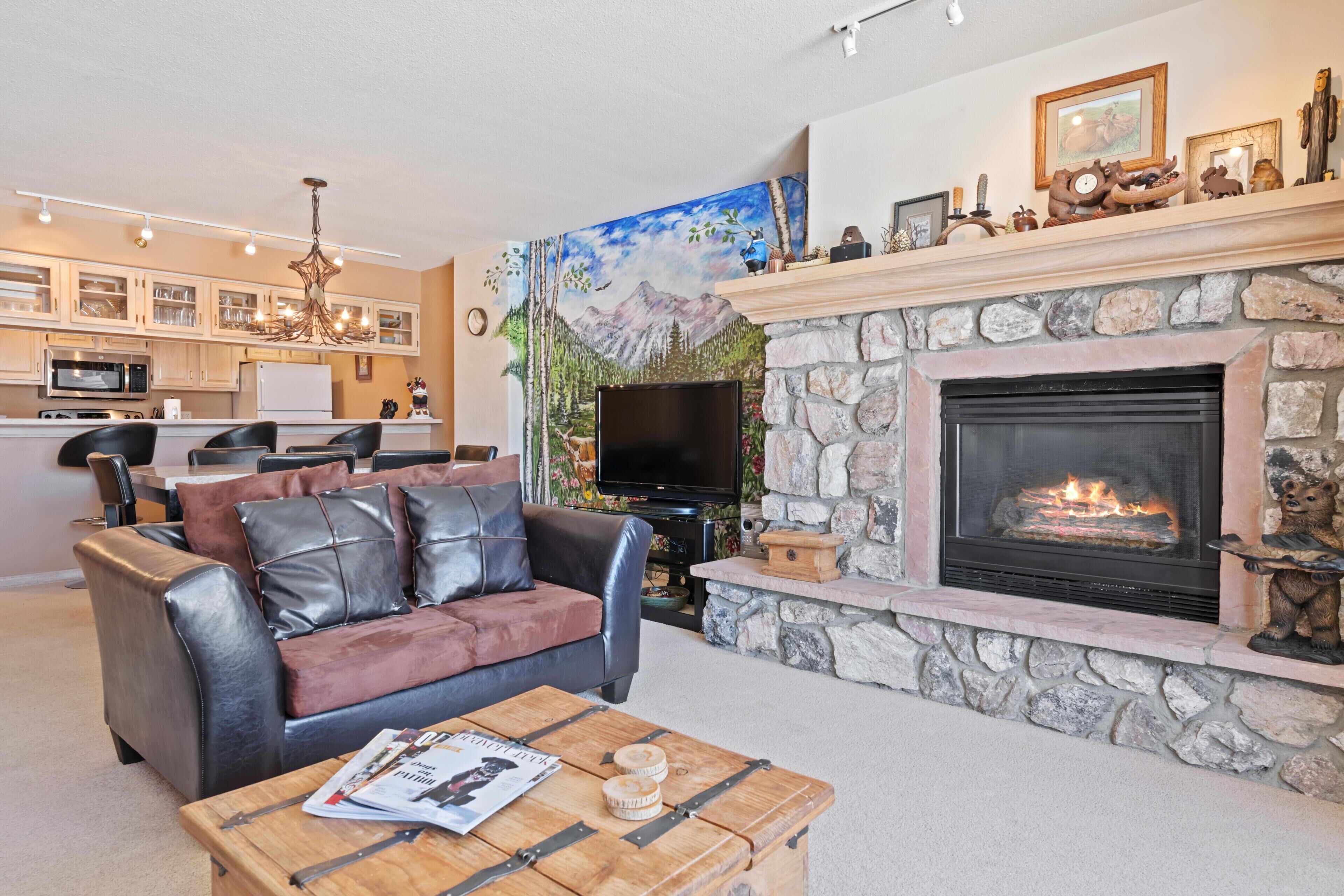 A living room with a fireplace, leather sofa, coffee table, and a TV.
