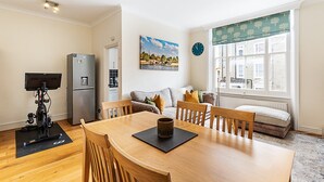 A modern living space with a dining area, a sofa, a window with a view, and a refrigerator. - Traditional Earl’s Court Apartment (London)