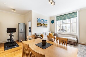 Ein moderner Wohnraum mit Essbereich, einer Couch, einem Fenster mit Blick und einem Kühlschrank.