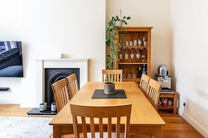 Ein Esszimmer mit Holztisch, Stühlen, Kamin, Bücherregal und Fernseher.