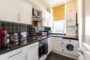 Eine moderne Küche mit Gasherd, Kaffeemaschine, Toaster und Waschmaschine.