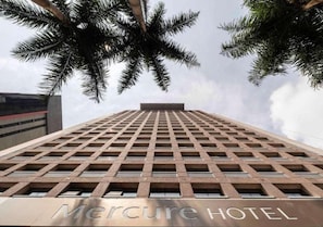 Ein hohes Gebäude mit einer gitterartigen Fassade, auf dem unteren Teil ist 'Mercure HOTEL' sichtbar.