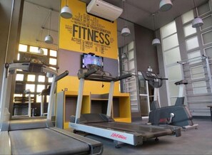 Ein Fitnessraum mit Laufbändern, einem Ergometer und einer Gewichtbank.
