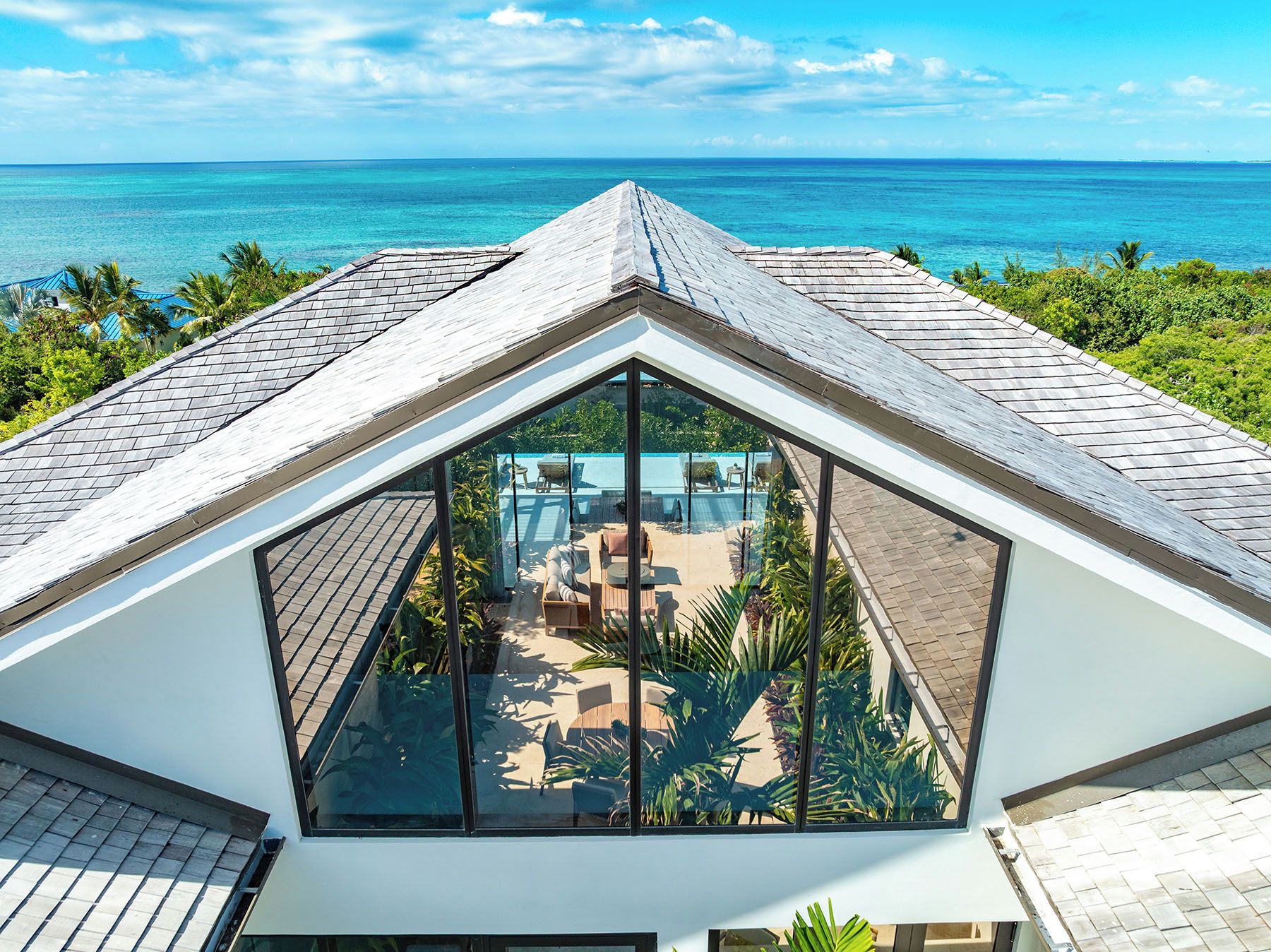 Un bâtiment moderne doté d’une terrasse fermée par des baies vitrées, offrant une vue sur une mer d’un bleu profond.