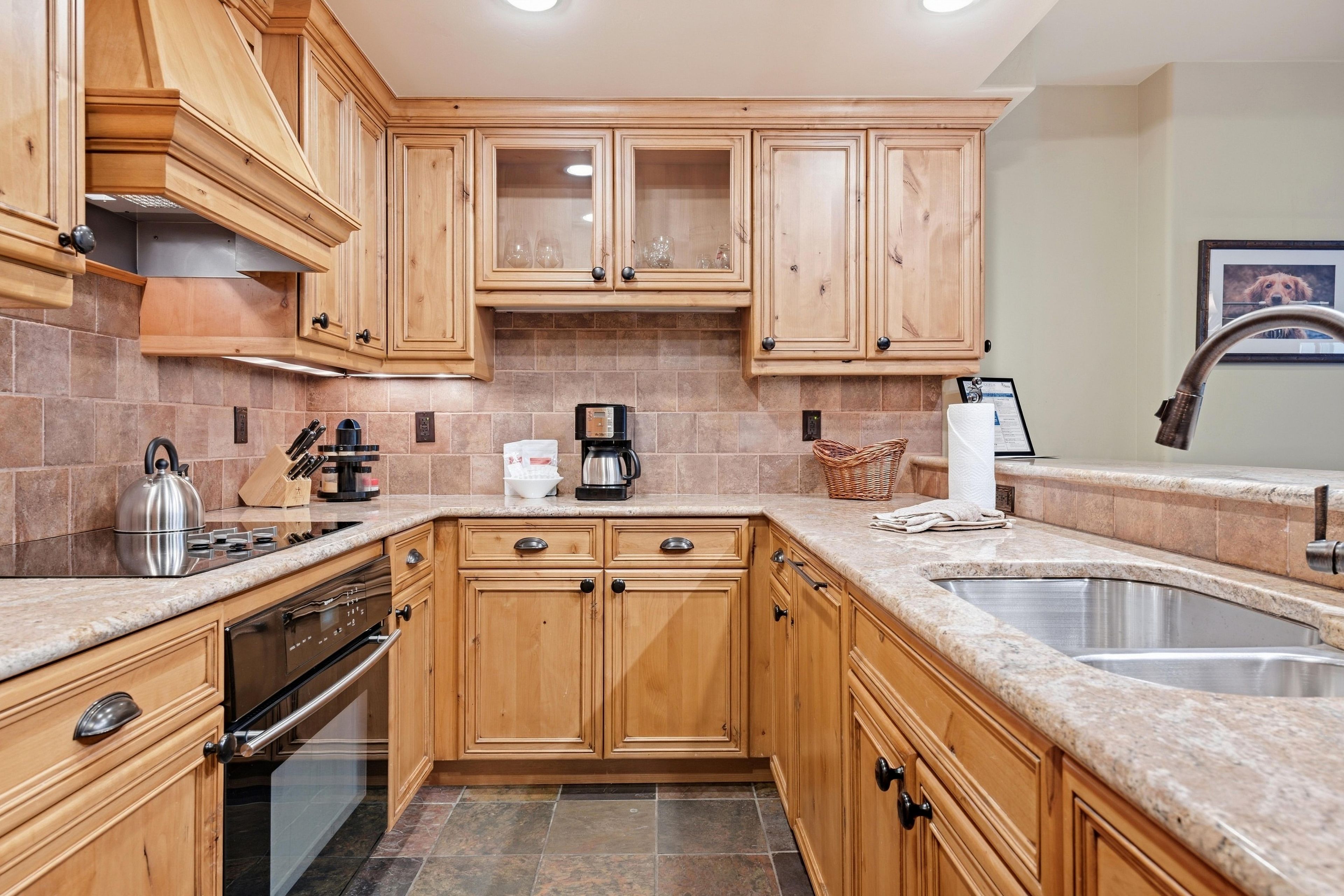 A kitchen with wooden cabinets, a stainless steel sink, and a built-in oven.