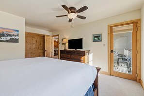 A bedroom with a bed, a ceiling fan, a TV, wooden furniture, and a door leading to an outdoor area. - Borders Lodge L208 2BD Beaver Creek Ski-in, Ski-out Condo (Avon)
