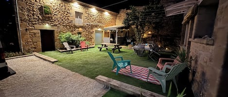 A stone building with a patio area, outdoor seating, and a barbecue setup.