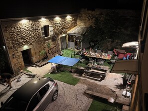 Un espacio de comedor al aire libre con un muro de piedra, un coche y una mesa con sillas.