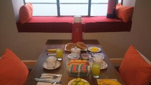 Ett frukostbord med tallrikar fyllda med ägg, avokado och en banan, en termos och en kanna med juice.