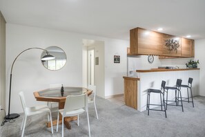 A modern kitchen with wooden cabinets, a round table with chairs, and a bar area with stools. - Cozy Lake Dillon Condo: Perfect For Leaf Peeping! (Dillon)