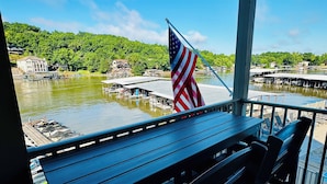 Ein überdachter Außenbereich mit Blick auf einen See, angestoßenen Booten und einer Flagge.