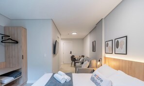 A hotel room with a bed, a desk, a chair, a wardrobe, and a door. - Studio in Center of Rosa, Rooftop w/ Pool Rso0003 (Imbituba)