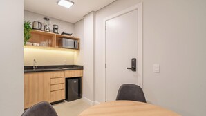 A compact kitchen with a microwave, coffee maker, and blender on the countertop, a sink, and a compact refrigerator. - Studio in Center of Rosa, Rooftop w/ Pool Rso0003 (Imbituba)