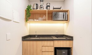 A compact kitchen with a sink, countertop, wooden cabinets, a dishwasher, and a microwave. - Studio in Center of Rosa, Rooftop w/ Pool Rso0003 (Imbituba)