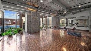 Un espacio interior con suelo de madera, ventanas grandes y equipo de ejercicio.