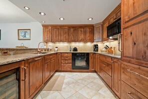 A kitchen with wooden cabinets, a built-in oven, and a microwave. - Borders Lodge L303 2BD Beaver Creek Ski-in, Ski-out Condo (Avon)