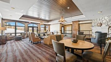 A spacious lounge with a high ceiling, large windows, and a fireplace.