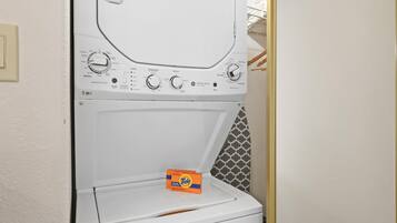 Una lavadora de carga frontal con detergente Tide, perillas de control y una pared con diseño.