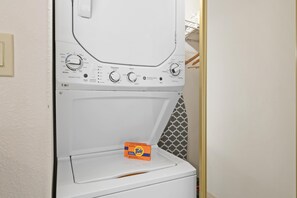 Una lavadora de carga frontal con detergente Tide, perillas de control y una pared con diseño.