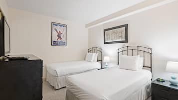 Habitación de hotel con dos camas, un escritorio, un aparador, un cuadro enmarcado y un cartel en la pared.