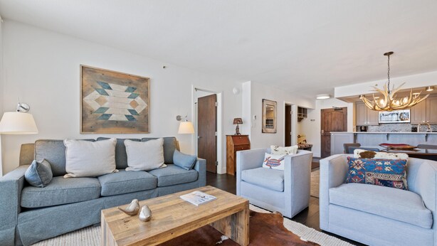 Un salon moderne comprenant un canapé, un fauteuil, une table basse et un tapis en peau de vache.