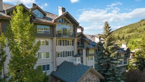 Un hôtel à plusieurs étages, doté d’une entrée en pierre, de balcons et offrant une vue sur le paysage environnant.