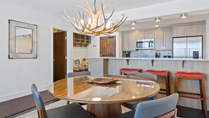 Une cuisine moderne dotée d’un îlot central, d’appareils électroménagers en acier inoxydable et d’un lustre original en forme de bois de cerf.