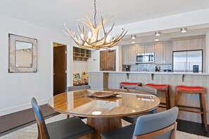 Eine moderne Küche mit einer Kochinsel, Edelstahlgeräten und einem markanten Chandelier aus Geweihen.