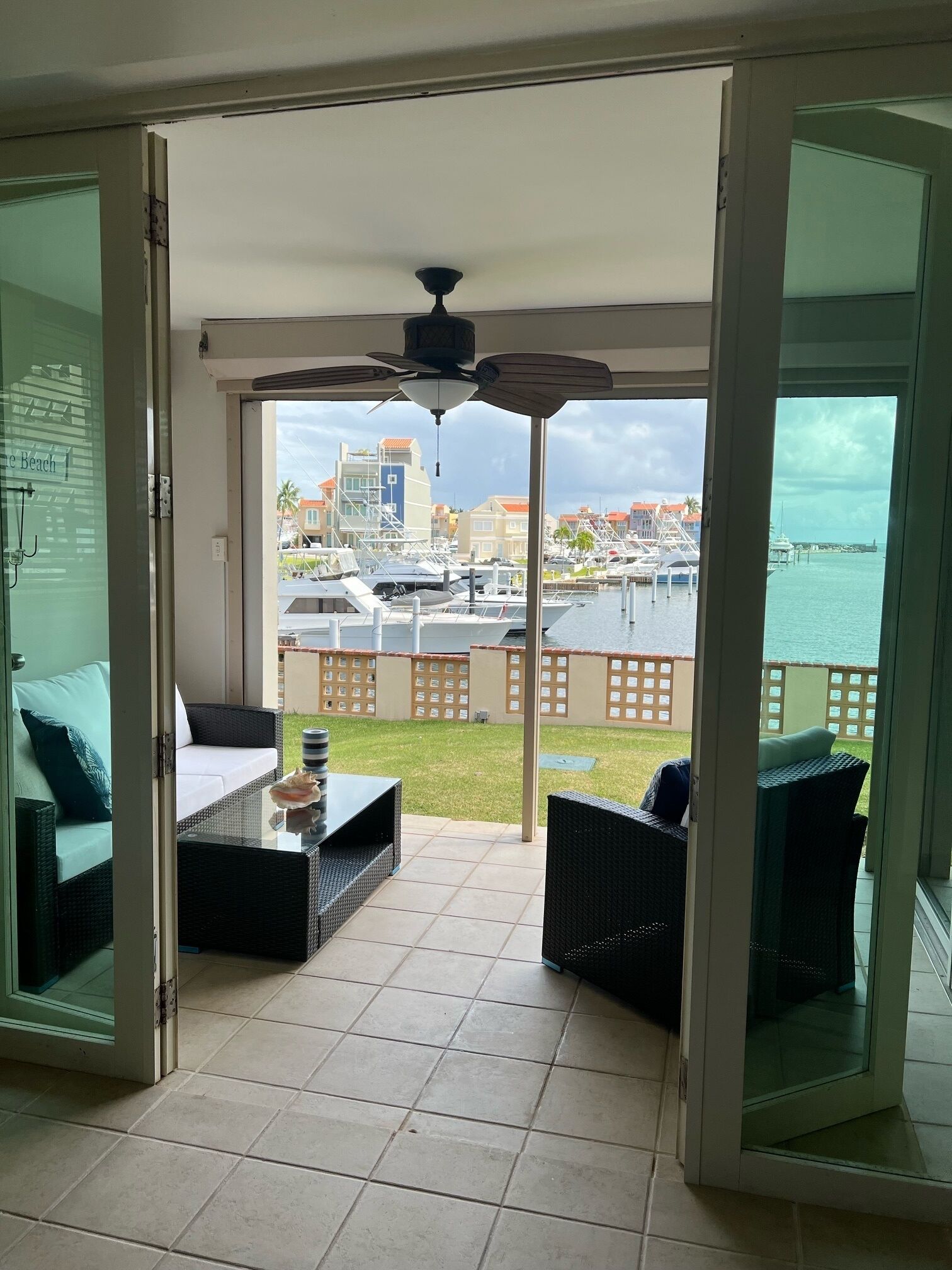 A balcony with a view of a marina and buildings, furnished with wicker chairs and a table.